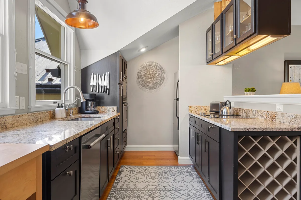 A contemporary kitchen with granite countertops, sleek cabinetry, a kitchen island, and modern appliances. The space is designed for both style and function, with plenty of room for cooking and entertaining guests.