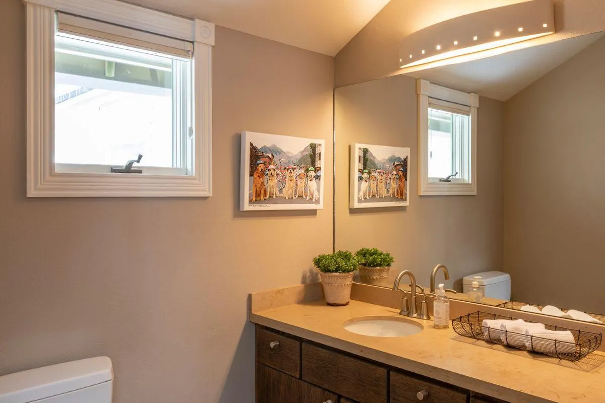 A stylish full bathroom with a modern sink, framed artwork, fresh towels, and a potted plant. The space feels calming and fresh—perfect for settling in and refreshing after travel.